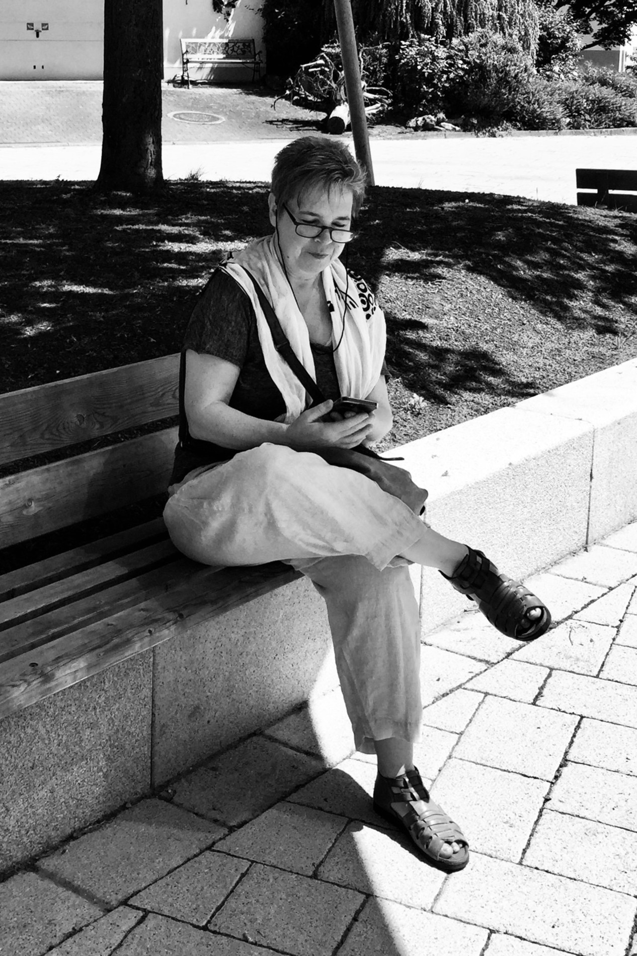 Frau recherchiert auf einer Mauer etwas am IPhone