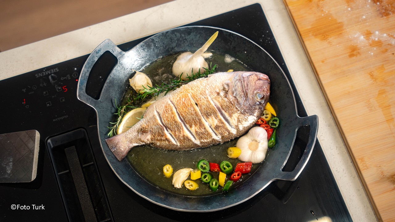 eine Eisenpfanne auf einem Herd, inklusive Fisch, Foto Turk